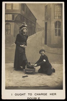A shoeshine boy cleans the boots of a man in drag, c1905. Creator: Unknown.