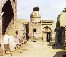 View of a courtyard, adobe buildings, and a bird's nest atop a dome, between 1905 and 1915. Creator: Sergey Mikhaylovich Prokudin-Gorsky.
