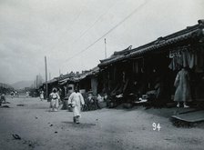 A line of shops beside a dusty street, with telegraph poles overhead, in Korea, c1900. Creator: Unknown.