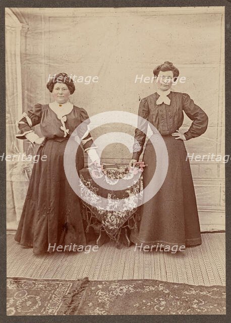 Two women standing at a table holding flowers, about 1875. Creator: Unknown.
