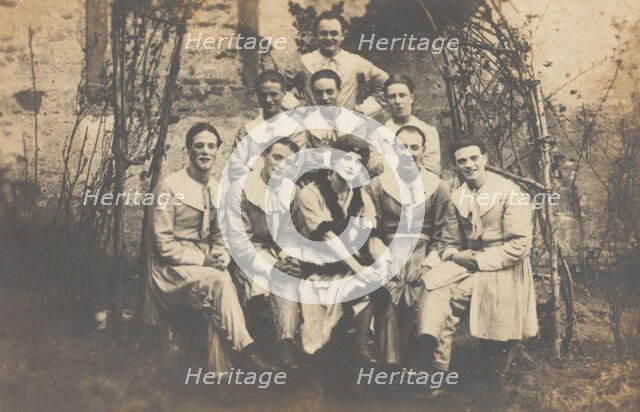 Concert party performers, one in drag, pose for a group portrait, (between 1910 and 1919?). Creator: Unknown.