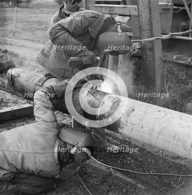 Two welders at work on the Mersey oil pipeline, 24/09/1967. Creator: John Laing plc.