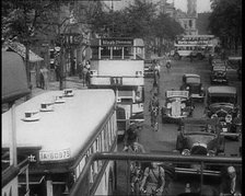 Buses, Cars and People on Bikes Driving Down the Road, 1933. Creator: British Pathe Ltd.