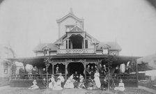 Frances Benjamin Johnston and family on porch and in front of house, between 1890 and 1910. Creator: Unknown.