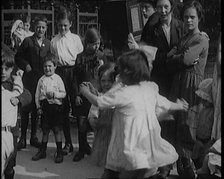 A Group of Civilian Children Dancing in Front of a Hurdy Gurdy Watched by a Small Crowd, 1920. Creator: British Pathe Ltd.