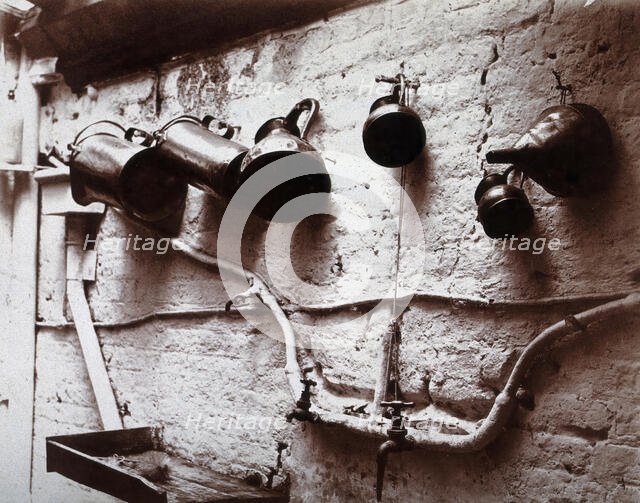 Measuring jugs and a funnel hung on a wall in the Red Cross pharmacy in London, c1890s. Creator: Unknown.