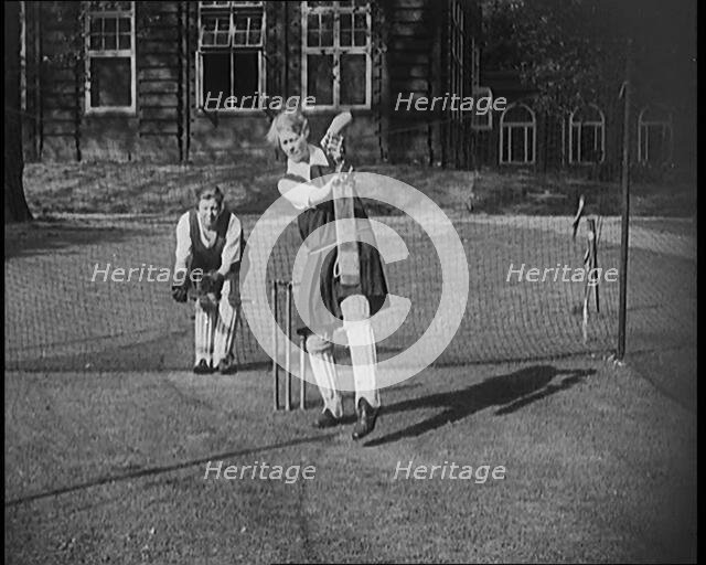 Two Female Civilians Wearing Gymslips and Batting Pads Preparing to Bat in a Playing Field, 1920. Creator: British Pathe Ltd.