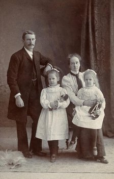 Unidentified family with two girls holding dolls. Creator: Priyalalls Photography.