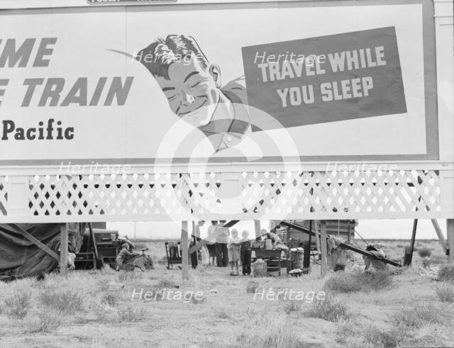 Billboard along U.S. 99 behind which three destitute families..., Kern County, California, 1938. Creator: Dorothea Lange.