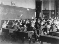 Children seated at desks in Washington, D.C. classroom, stretching, (1899?). Creator: Frances Benjamin Johnston.