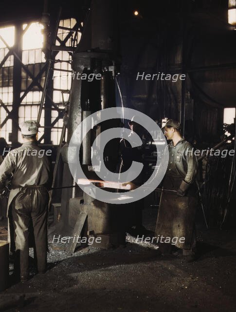 Working with a small steam drop hammer, blacksmith shop, Santa Fe RR shops, Topeka, Kansas, 1943. Creator: Jack Delano.