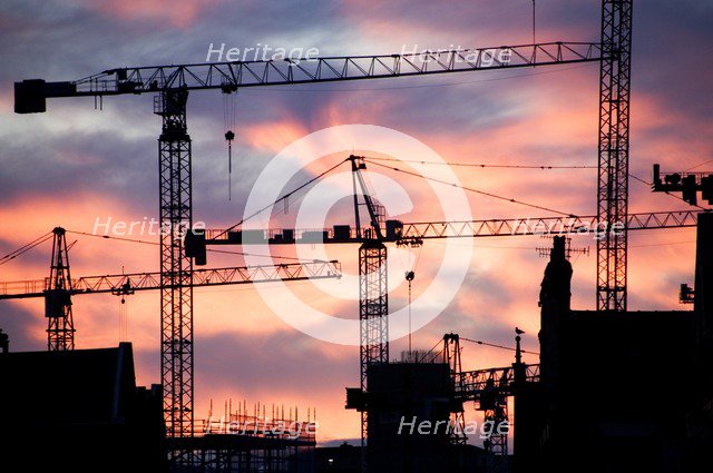 A building site at sunset with cranes silhouetted against a red sky, 2007. Artist: Historic England Staff Photographer.