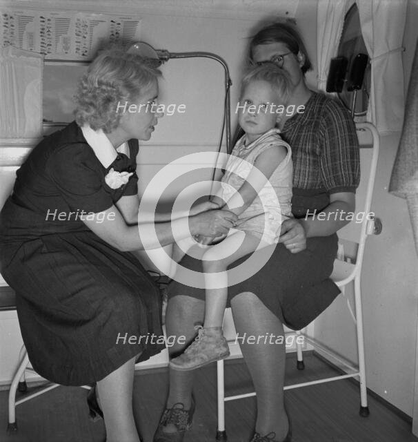 In trailer clinic, the nurse consults the migrant..., Merrill FSA camp, Klamath County, Oregon, 1939 Creator: Dorothea Lange.