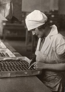 A woman uses a piping bag to decorate chocolates, Rowntree factory, York, Yorkshire, 1932. Artist: Unknown
