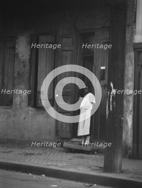 View from across street of a woman standing in a doorway in the French Quarter, New..., c1920-c1926. Creator: Arnold Genthe.