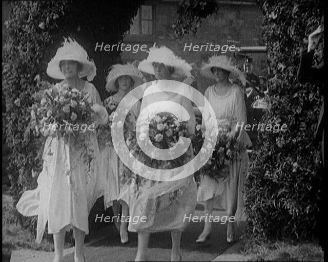 British Bridesmaids Walking Through a Flowery Arch, Holding Flowers, 1921. Creator: British Pathe Ltd.