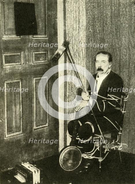 John Nevil Maskelyne performs a 'spirit cabinet illusion', c1910. Creator: Unknown.
