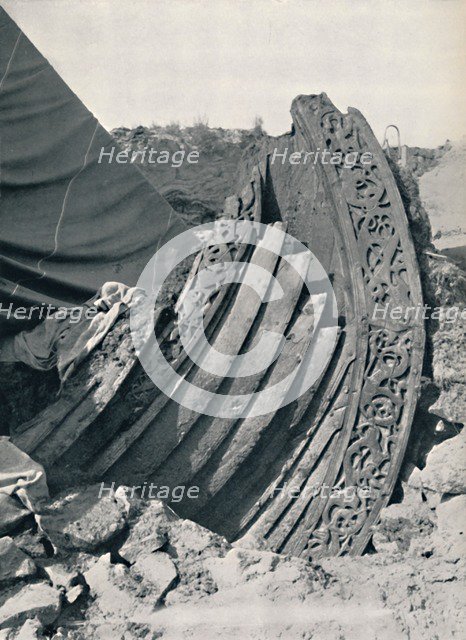 'The Oseberg ship in the mound, showing the carving on stem and railing', 1935. Artist: Unknown.