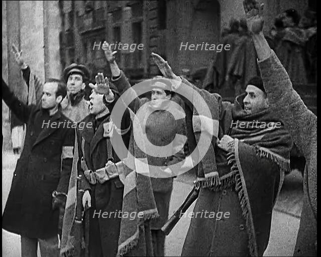 Armed Men and Civilians Making Fascist Salutes in a Street in Madrid, All Dressed in Thick..., 1939. Creator: British Pathe Ltd.