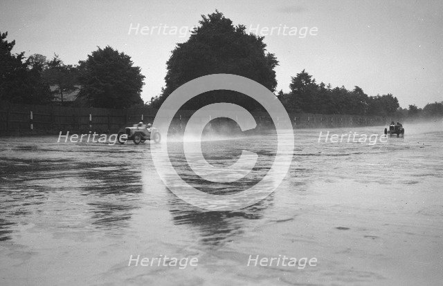 Austin 7 leading a MG in the wet at the LCC Relay GP, Brooklands, 25 July 1931. Artist: Bill Brunell.