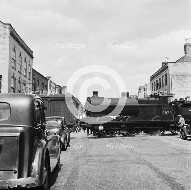 Goods vehicles being shunted across the un-gated level crossing in High Street, Tewkesbury, 1947. Creator: Marjory L Wight.