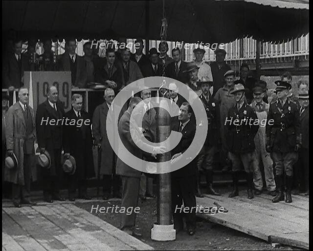 Two British Men Guiding a Time Capsule Being Lowered in the Ground With Various Civilians..., 1938. Creator: British Pathe Ltd.