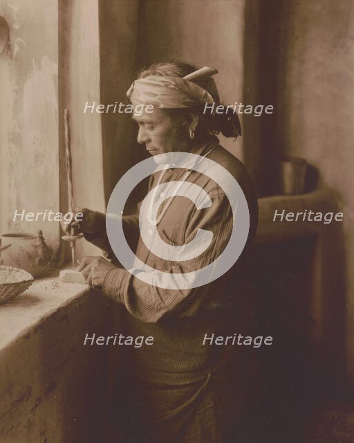Zuni Indian bead worker drilling holes in beads, c1903. Creator: Edward Sheriff Curtis.