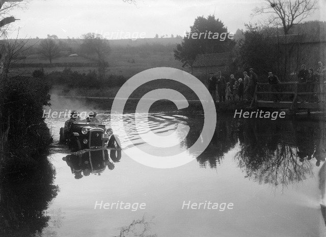 Austin Ulster driving through a ford during a motoring trial, 1936. Artist: Bill Brunell.