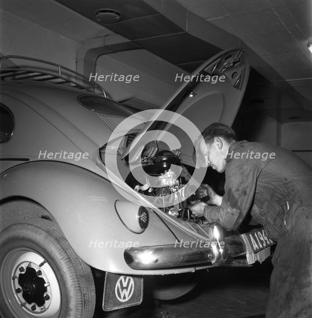 Car mechanic servicing a Volkswagen, Vallingby, Sweden, 1956. Creator: Unknown.