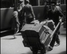 A Male Train Station Porter Pushing a Sack Barrow With Suitcases and Bags on it Along..., 1938. Creator: British Pathe Ltd.