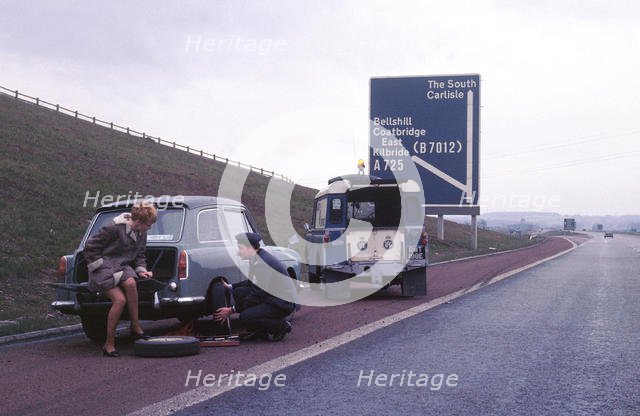 Austin A40 Farina having wheel changed by R.A.C breakdown assistance. Creator: Unknown.