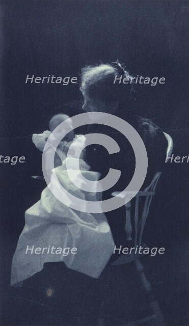 Woman, sitting in chair, holding an infant, full-length portrait, c1900. Creator: Sarah J. Eddy.