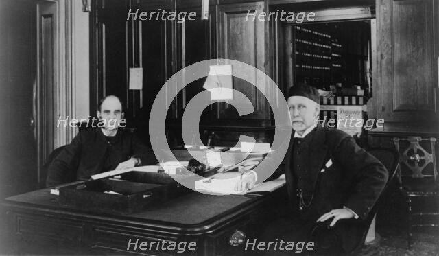 Two Treasury Department employees seated at desk in office, between 1884 and 1930. Creator: Frances Benjamin Johnston.