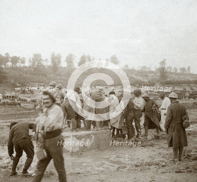 Soldiers queuing in the mud for water, Genicourt, northern France, c1914-c1918. Artist: Unknown.