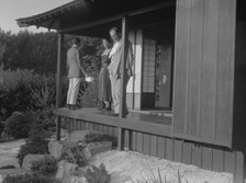 Three people standing on the porch of a Japanese-style building in a garden... A.W. Bahr, c1917-1934 Creator: Arnold Genthe.