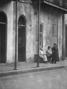 View from across street of people talking, New Orleans, between 1920 and 1926. Creator: Arnold Genthe.