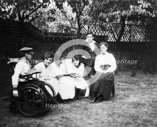 A physically disabled boy sitting in a wheelchair in a garden,  c1910/1925. Creator: Unknown.