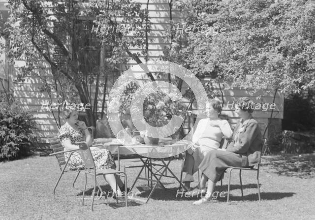Mrs. Mary Benson and two identified women seated outdoors at a table, between 1933 and 1942. Creator: Arnold Genthe.