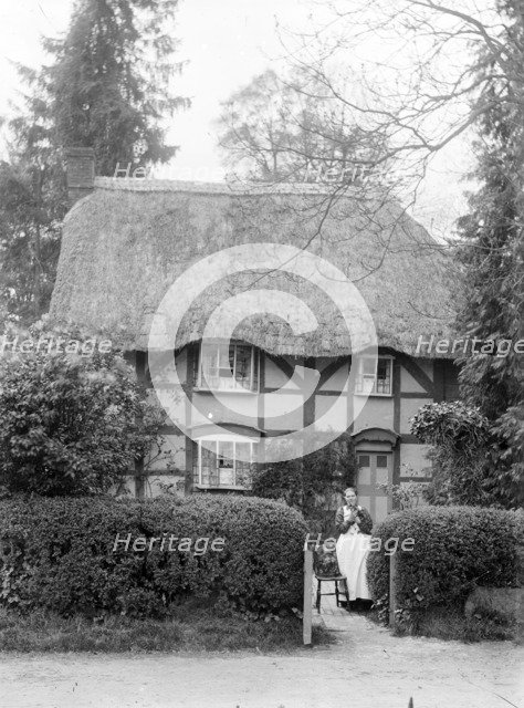 Woman holding her cat at the gate of her cottage, Uffington, Oxfordshire, c1916. Artist: FW Ault