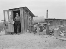 Mr. and Mrs. Wardlow at entrance to their dugout basement home, Dead Ox Flat, Oregon, 1939 Creator: Dorothea Lange.