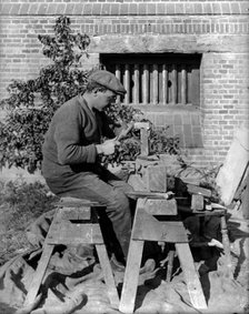 A craftsman shaping a brick on a bench at Great Dixter, Northiam, East Sussex, 1919. Artist: Nathaniel Lloyd