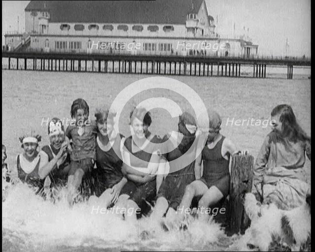 Women and Children Sitting on a Groyne, Splashing With Their Feet on a British Beach, 1920. Creator: British Pathe Ltd.