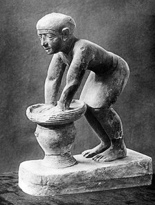 Figure of an Ancient Egyptian brewer pressing out fermented bread in a basket, c1910. Artist: Unknown