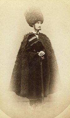 Full-length portrait of a man in cape and sheep skin hat, holding a rifle..., between 1870 and 86. Creator: Unknown.