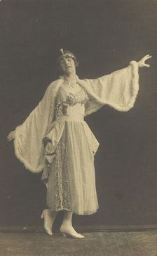 A prisoner of war in drag, wearing a dress and white cloak, poses...(between 1910 and 1919?). Creator: Albert Melzer.