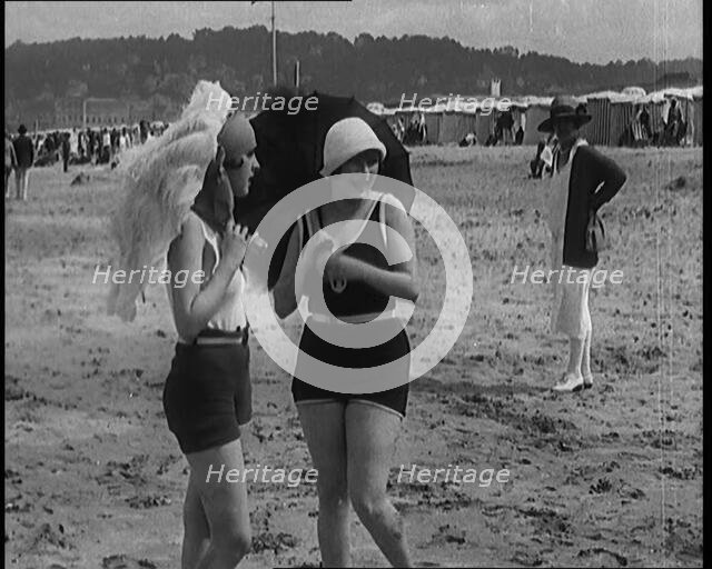 Two Young Female Civilians Wearing Swimsuits Holding Feathered Parasols on a Beach, 1920. Creator: British Pathe Ltd.