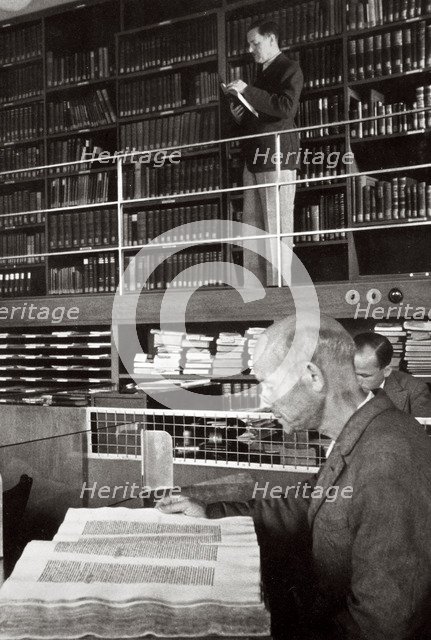 A labourer reads a book in a library, Germany, 1936. Artist: Unknown