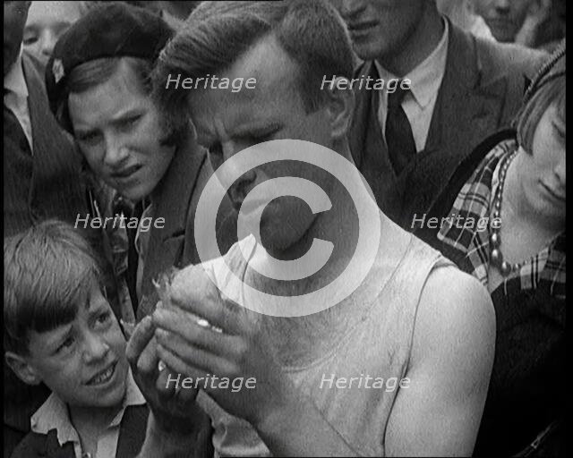 A Man Eating a Glass as the Crowd Behind Him Winces, 1921. Creator: British Pathe Ltd.