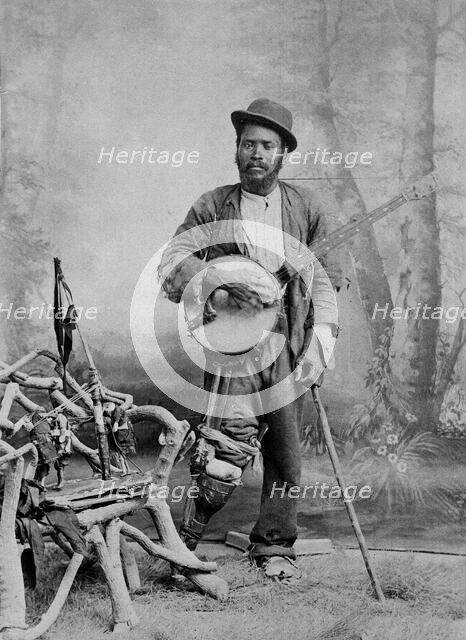 A black banjo player with a wooden leg, c1865. Creator: Unknown.