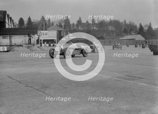 Two Bugatti Type 37s and an MG racing at Brooklands, Surrey, 1930s. Artist: Bill Brunell.